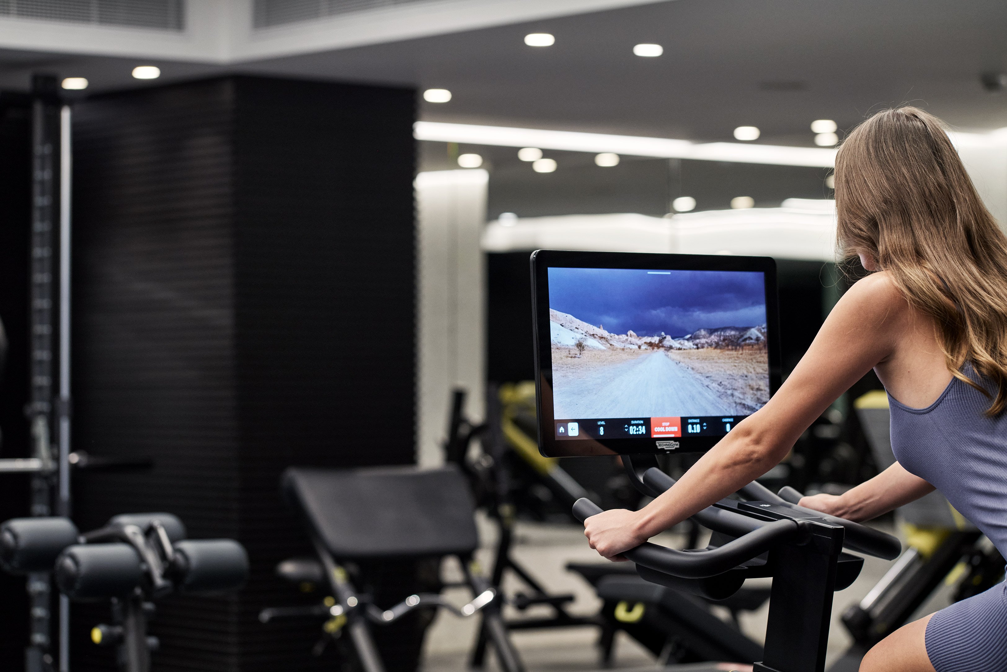 Person training on exercise bike with digital screen in gym.
