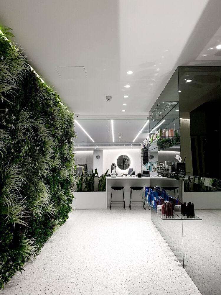 Bright corridor with green vertical garden and white floor.