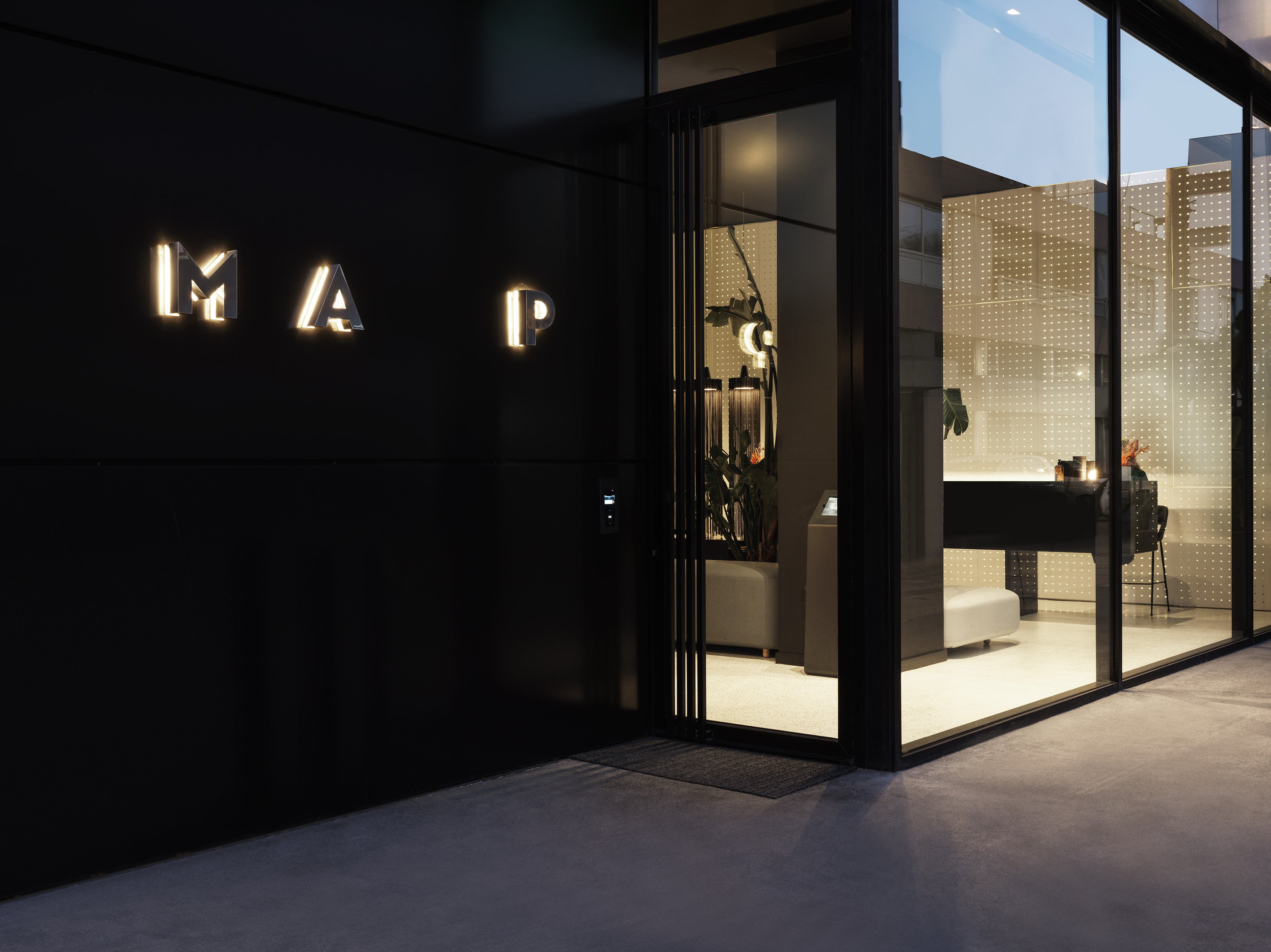 Exterior night view of MAP Hotel entrance with illuminated logo.