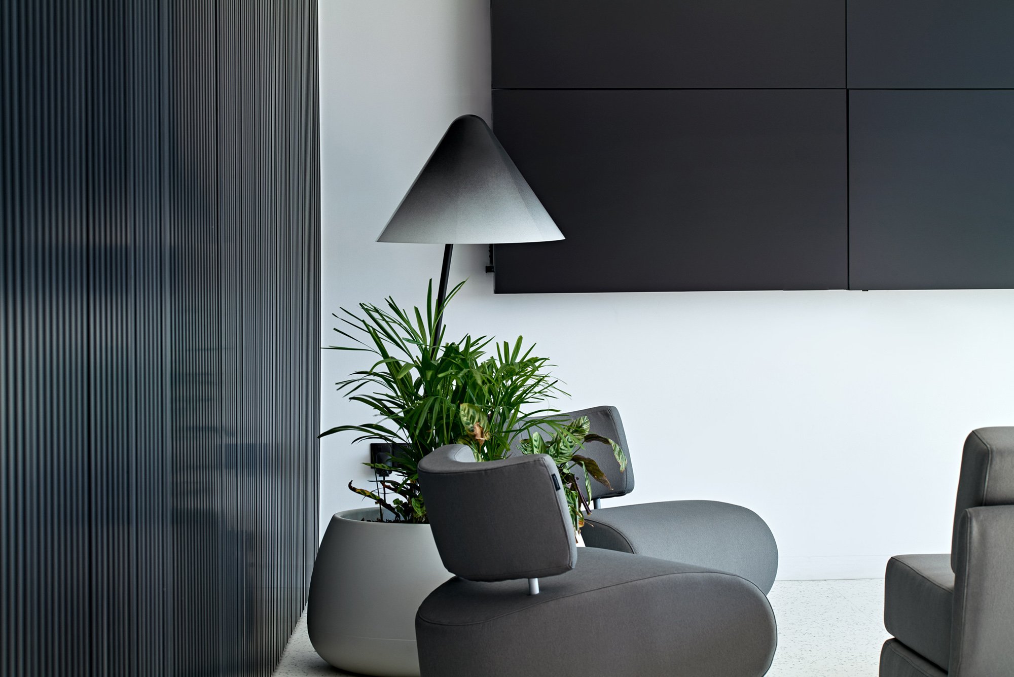Lounge corner with grey armchairs, floor lamp and indoor plants.