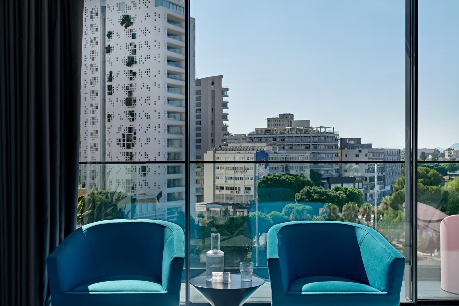 Balcony view with two blue armchairs and glass railing.