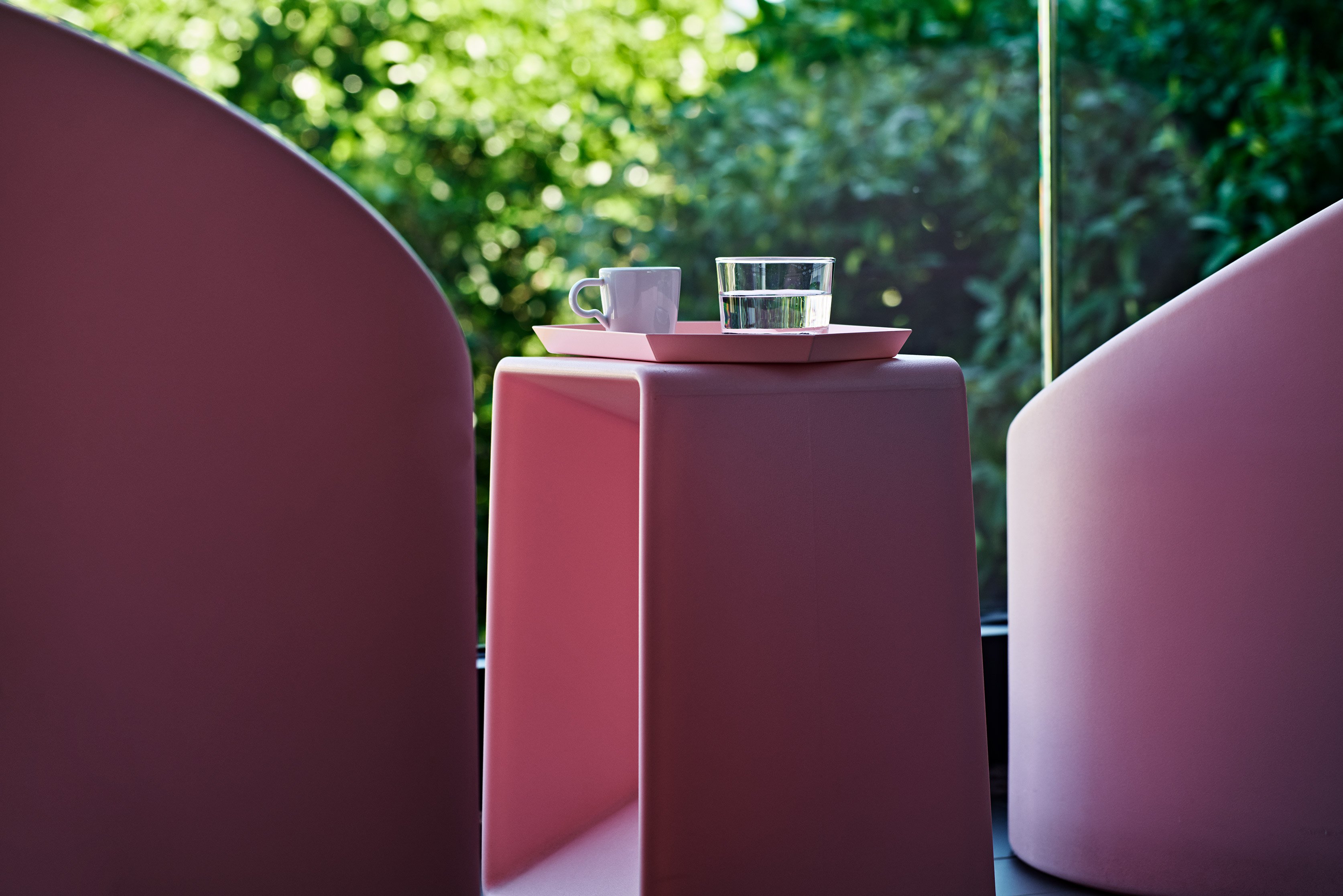 Close-up of pink balcony tables with glass and cup.