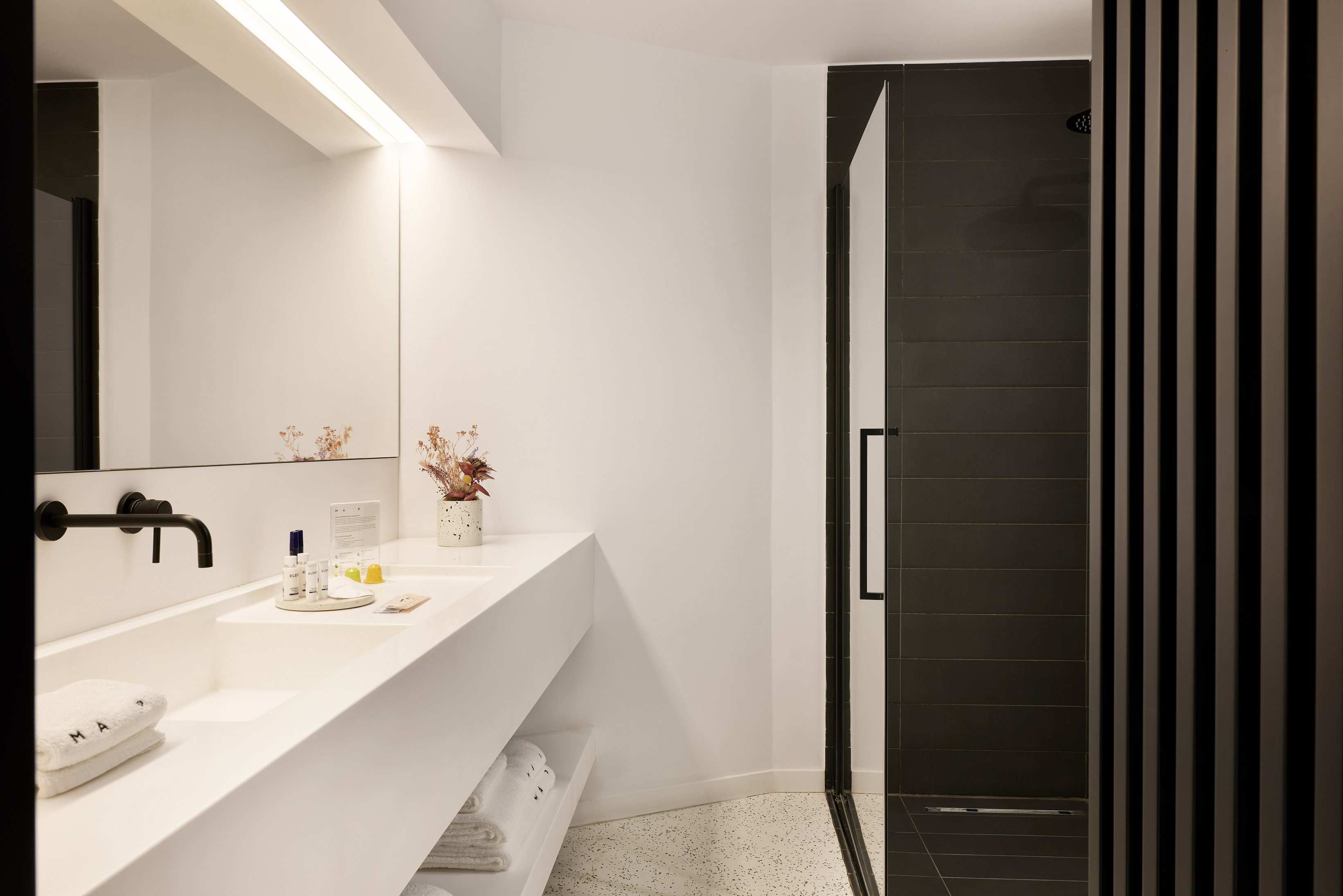 Bathroom with white sink, black shower wall and soft ceiling light.