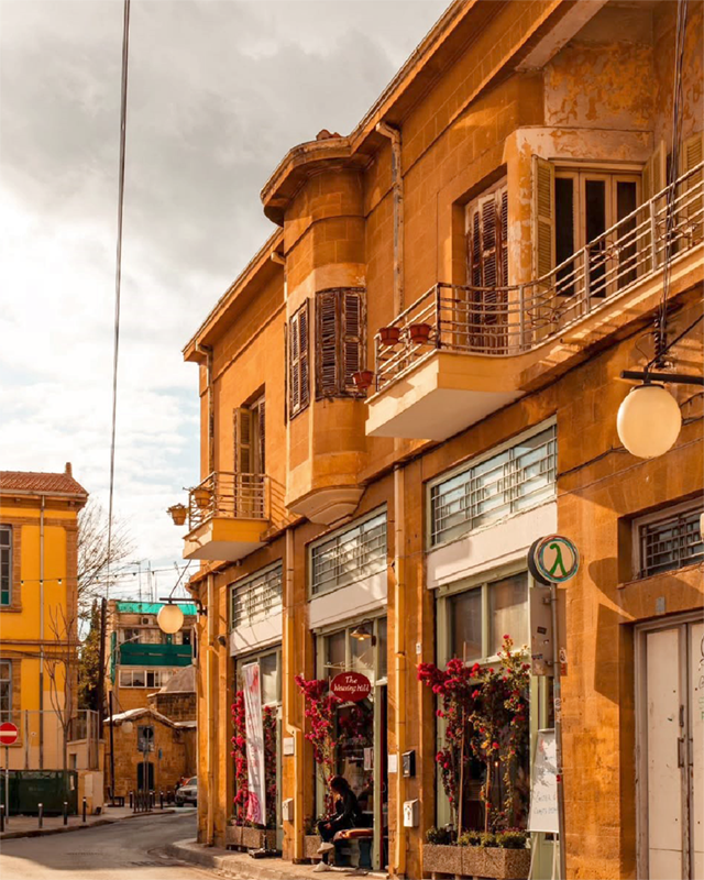Narrow street in old Nicosia lined with yellow stone buildings.