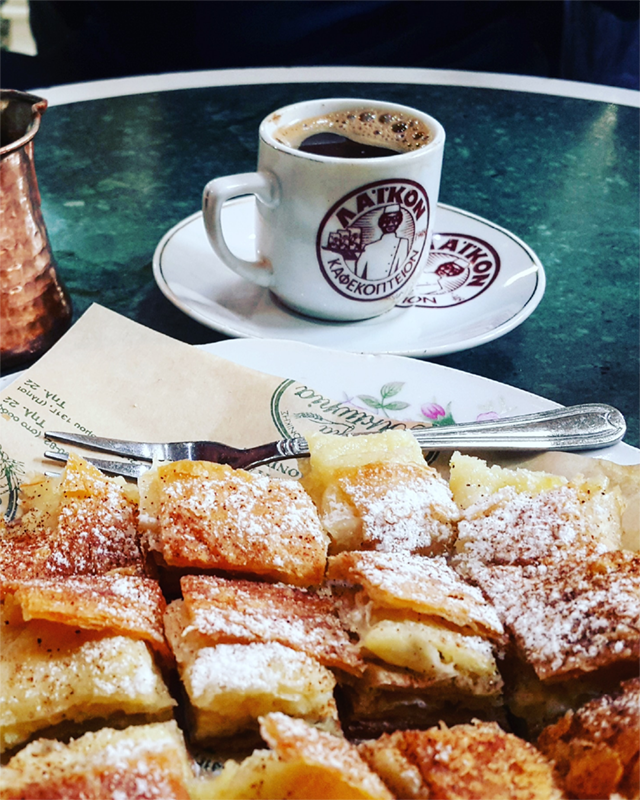 Cup of coffee and pastries served on a greenish table.
