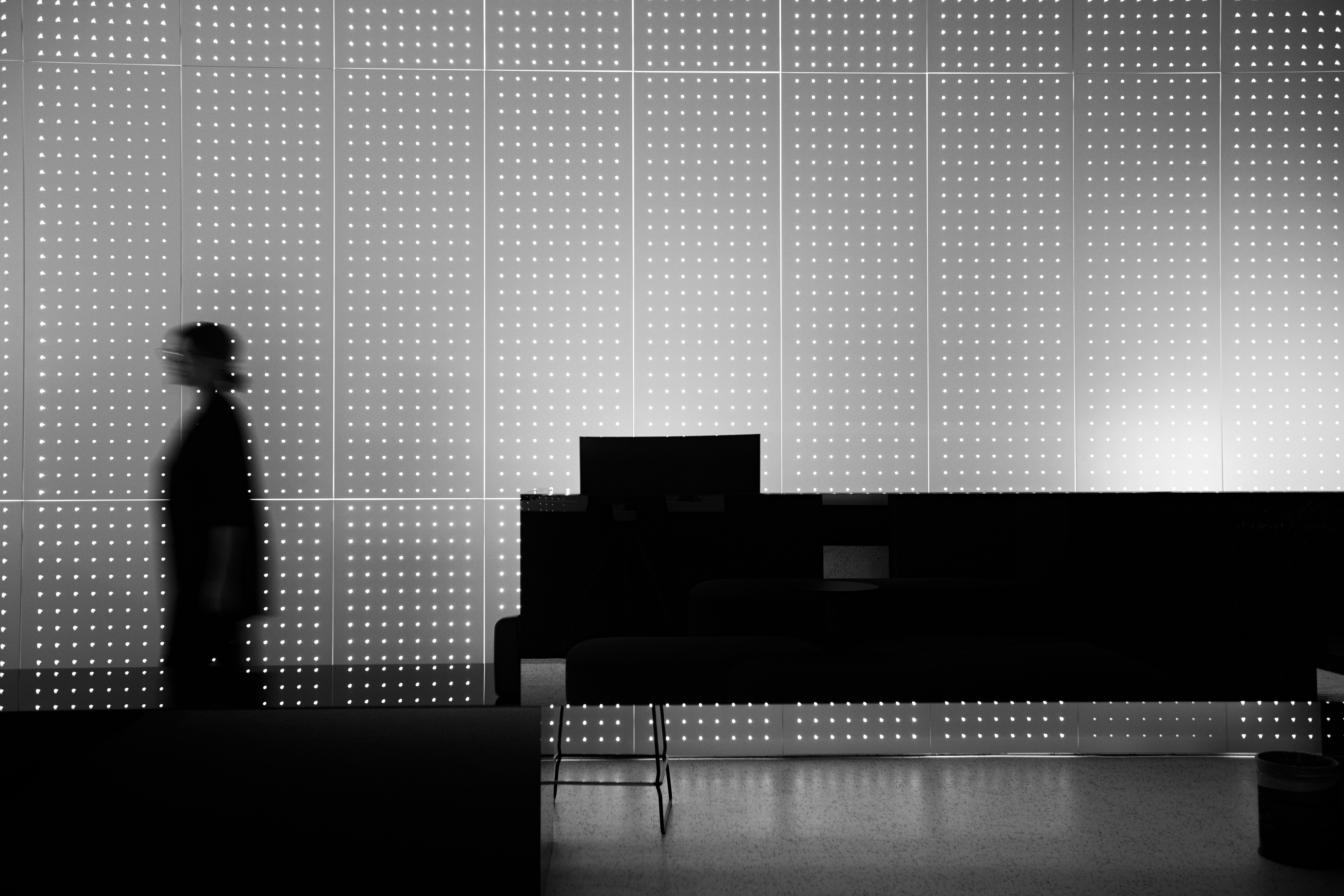 Lounge area with black furniture and dotted light wall in dim setting.