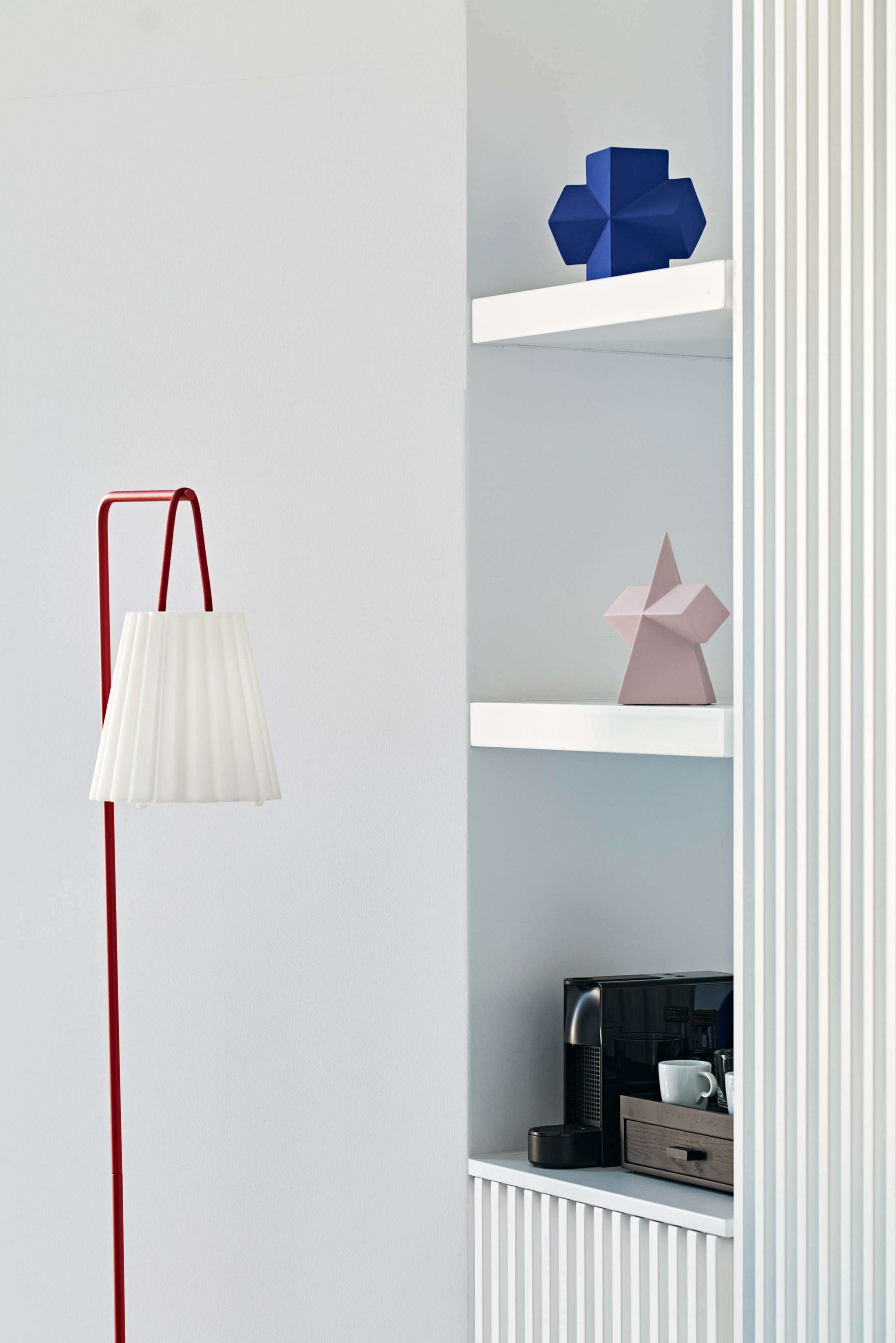 Interior corner with red floor lamp and minimalist shelves.