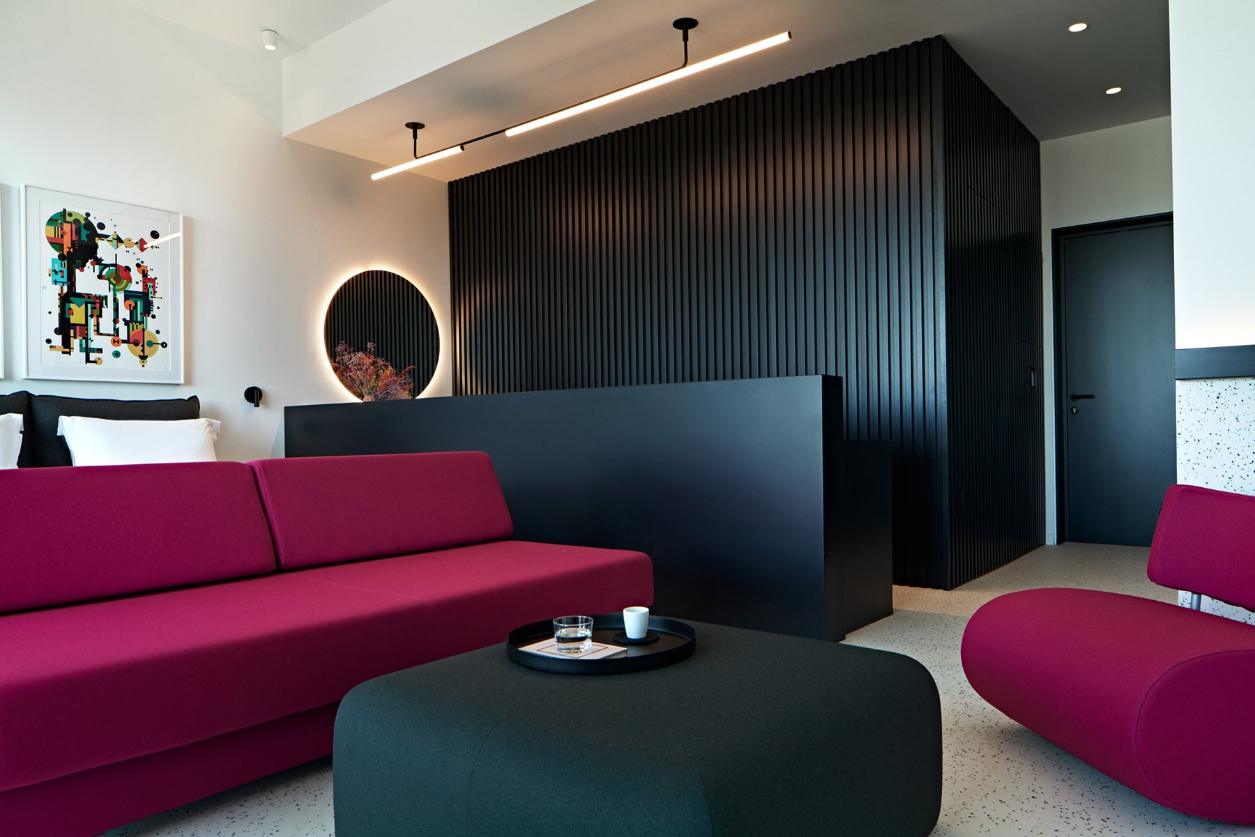 Living area with magenta sofa and dark feature wall.