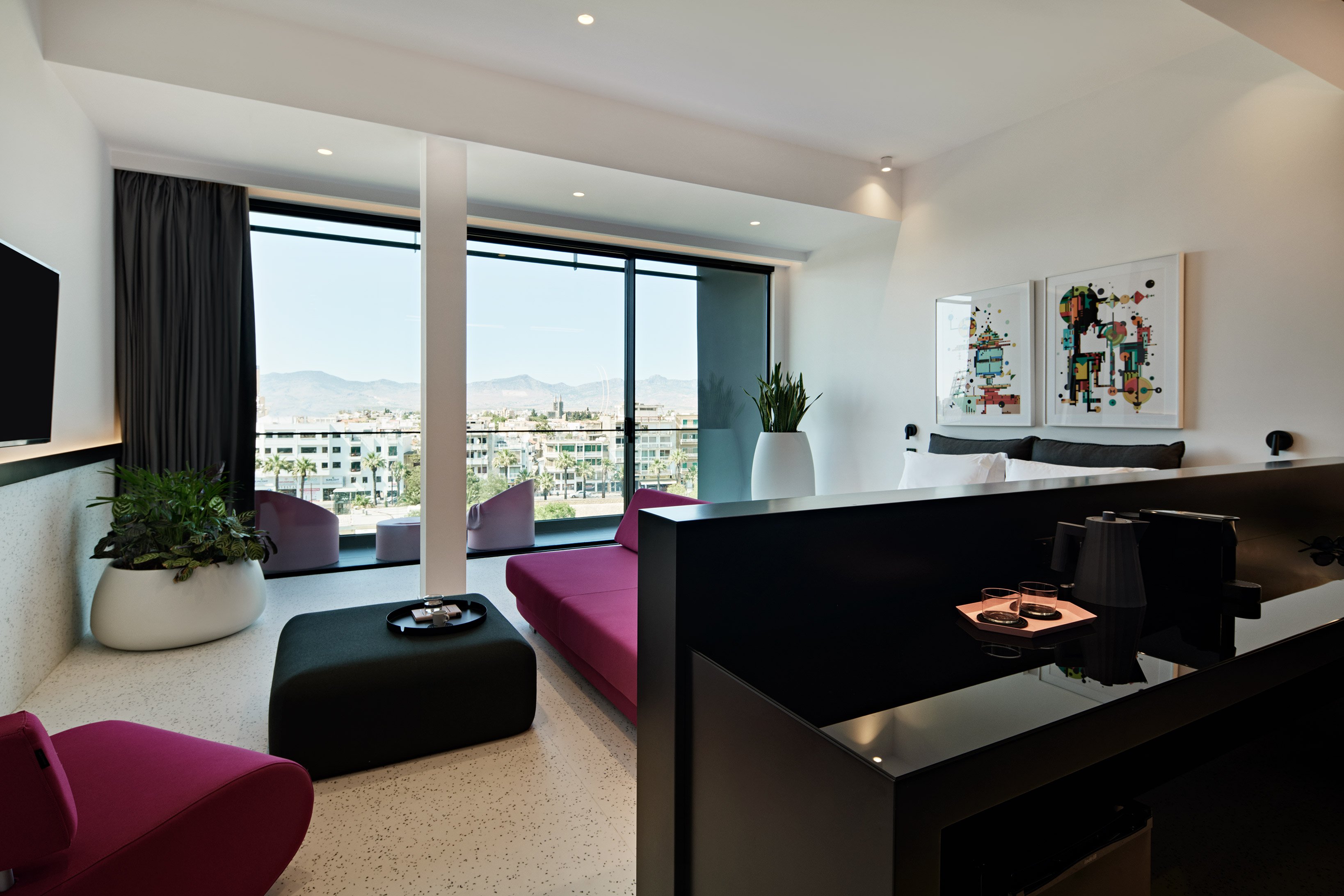 Bedroom with bed and seating area opening onto balcony.