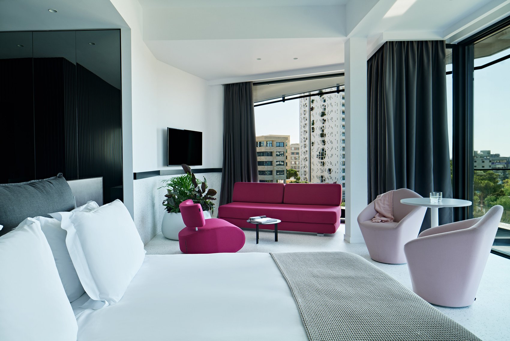 Spacious room with bed, pink sofa and floor-to-ceiling windows.