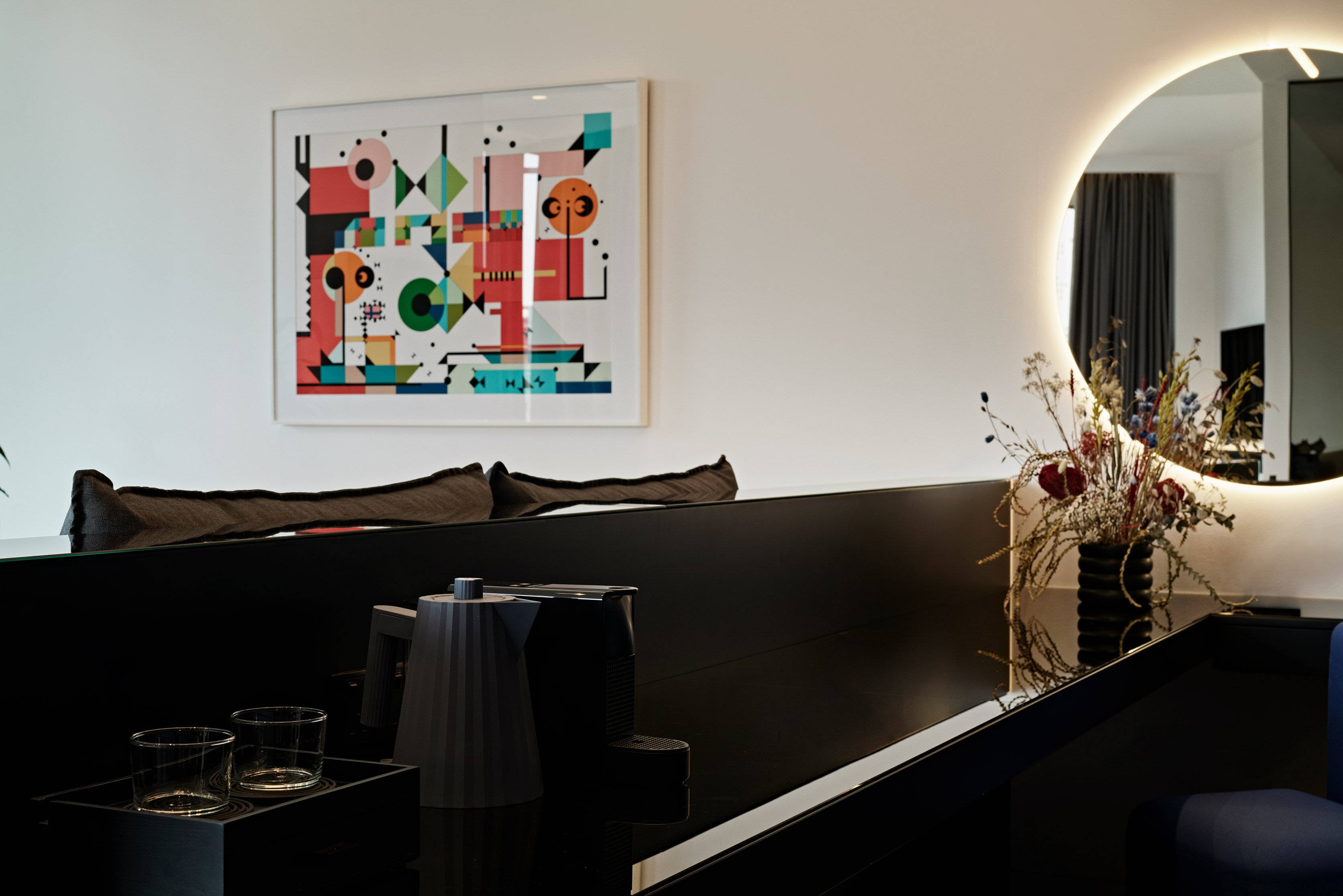 Close-up of wall artwork above dark sofa in hotel suite.