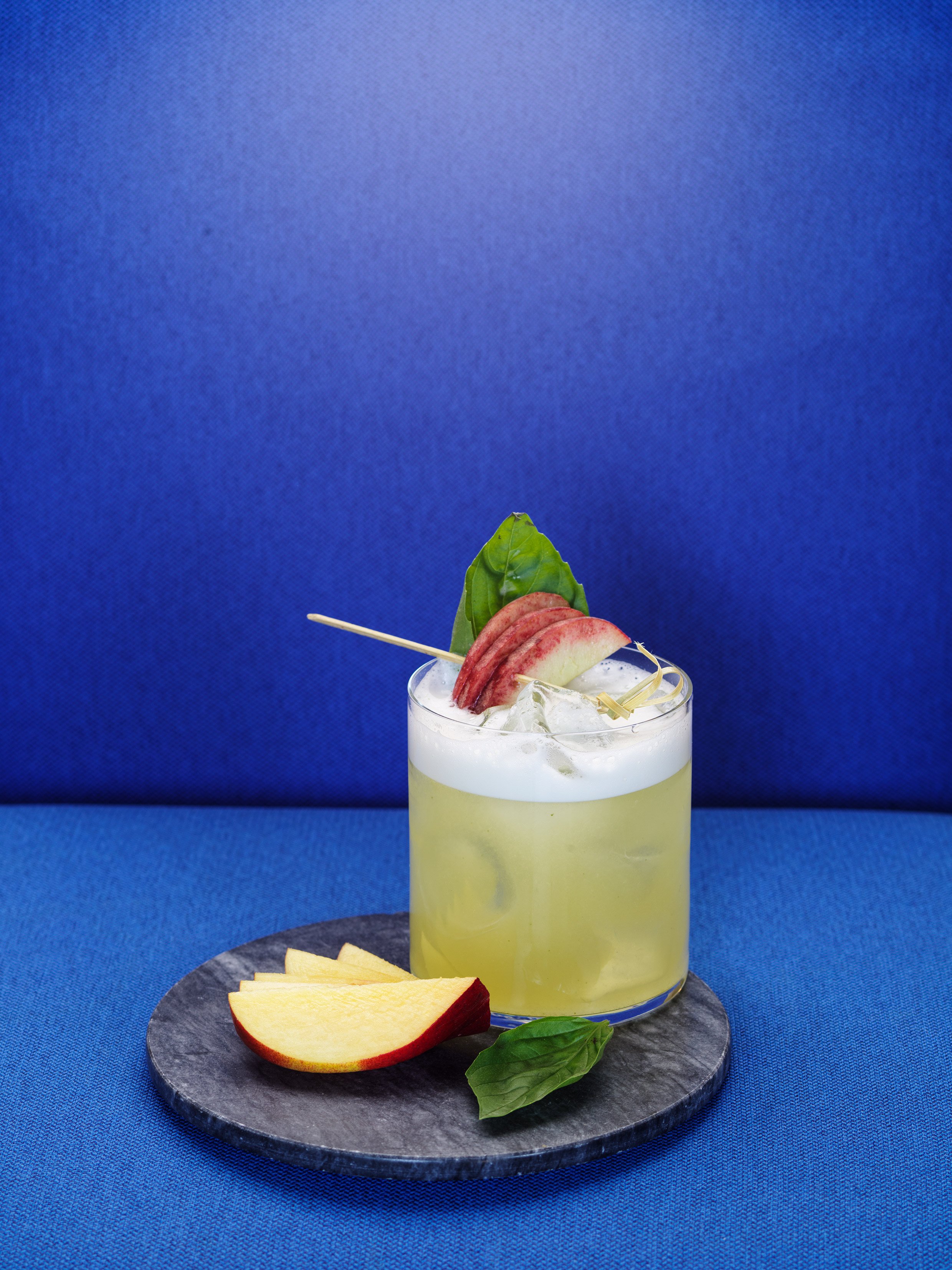 Yellow cocktail with mint and peach slices.