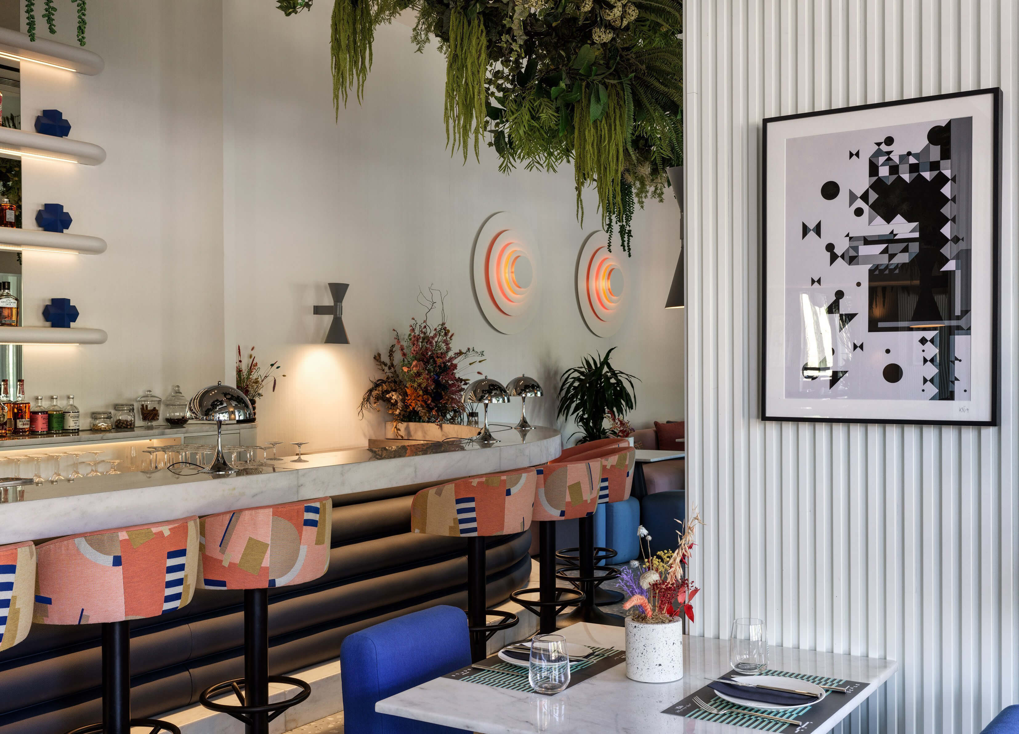 Restaurant interior with wall art, hanging greenery and modern lighting.